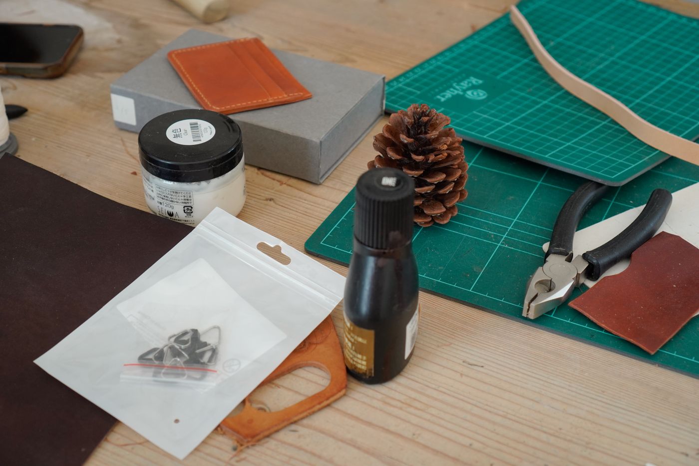 Leather swatches, edge dye and hardware on a workbench.