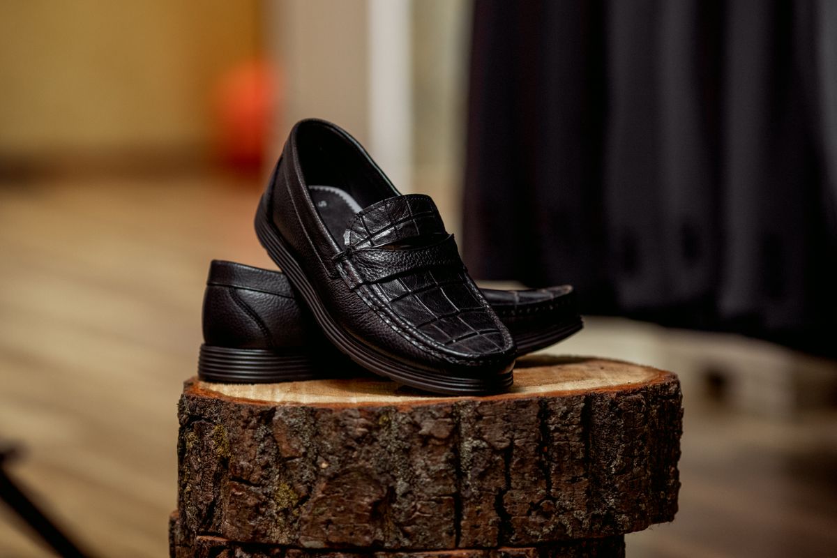 Black leather loafers resting on a wooden surface.